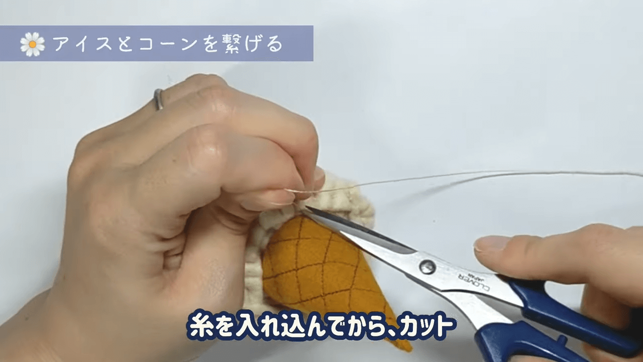 一周縫えたら玉留めをし、アイスとコーンの間に針を通して、さらに玉留め。 さらにアイスとコーンの間に針を通して、糸を引っ張りながらカットする。